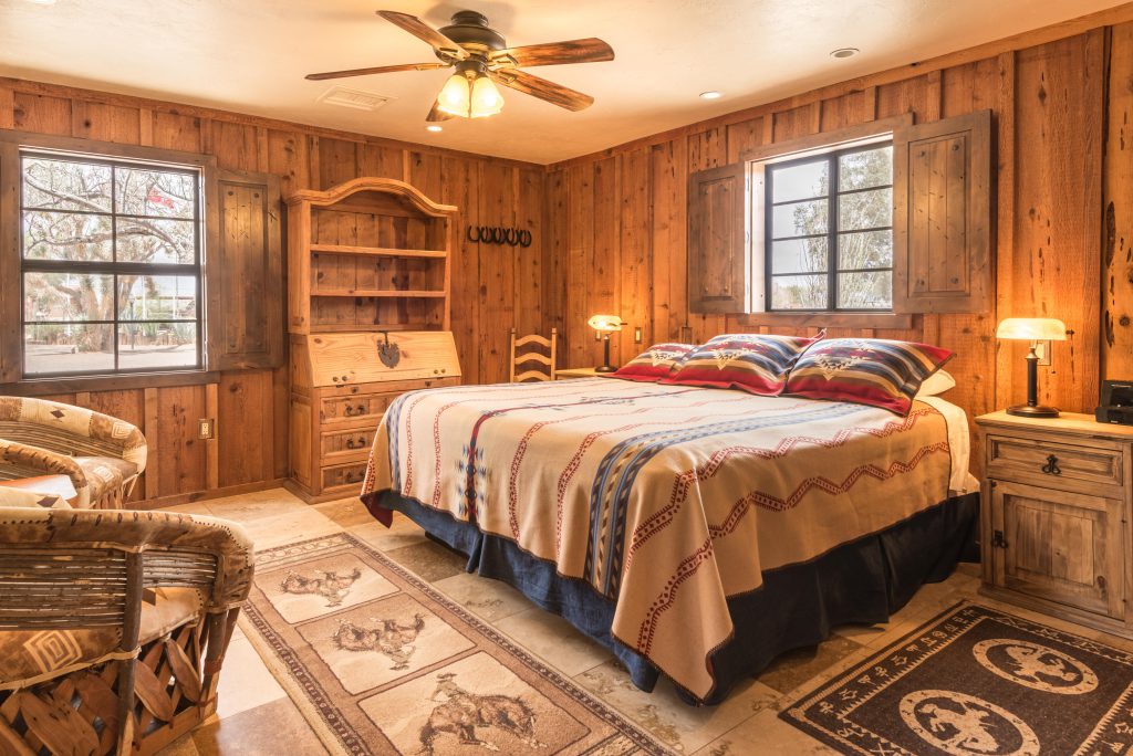 Slaapkamer met tweepersoonsbed in westernstijl op ranchvakantie