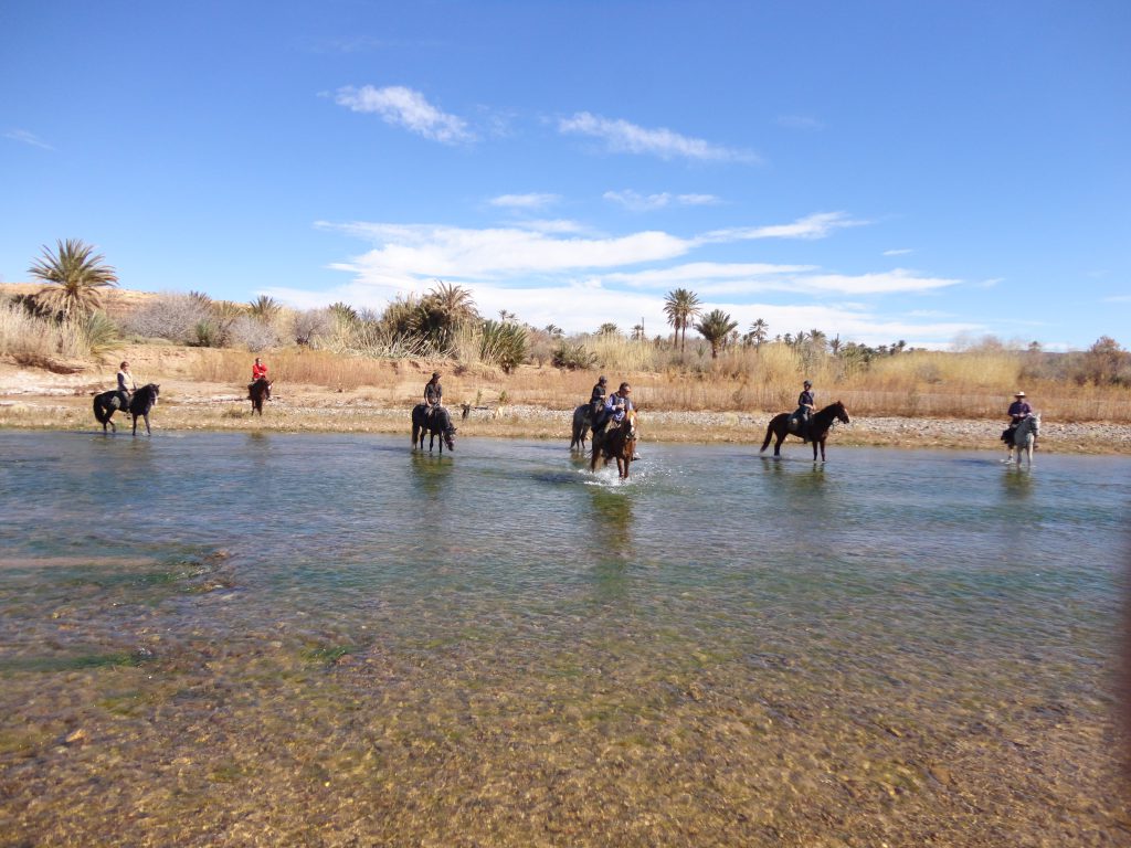 Groep ruiters steken een rivier over in Marokko