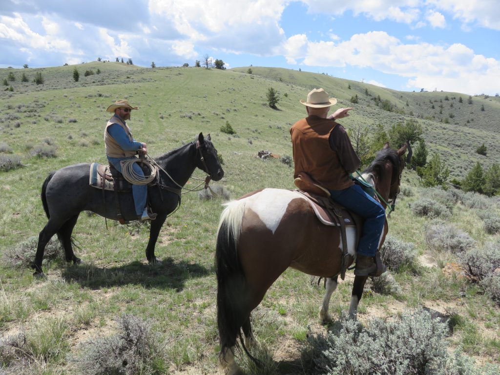 Twee cowboys tijdens een buitenrit op ranchvakantie in Wyoming