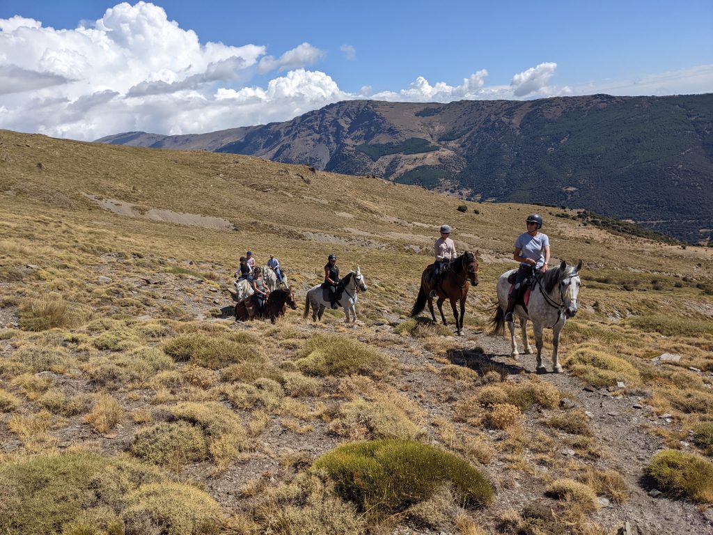 Groep ruiters en paarden paardrijden door de bergen tijdens trektocht in Spanje