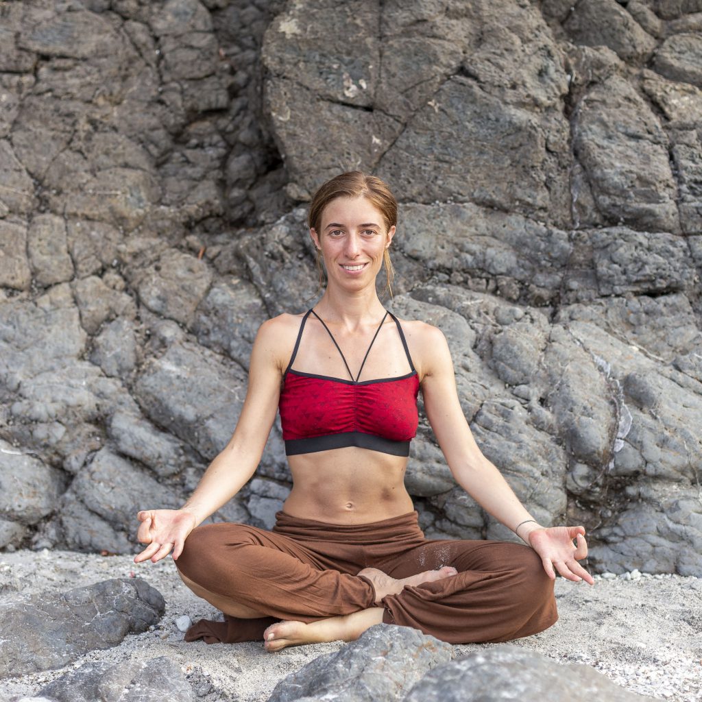 Vrouw zit in yoga positie voor rotsen