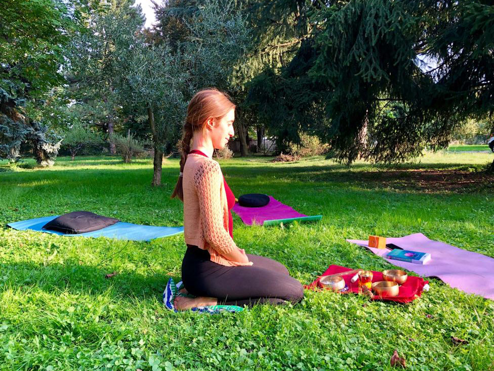 vrouw doet yoga in het gras omringd door yoga matjes