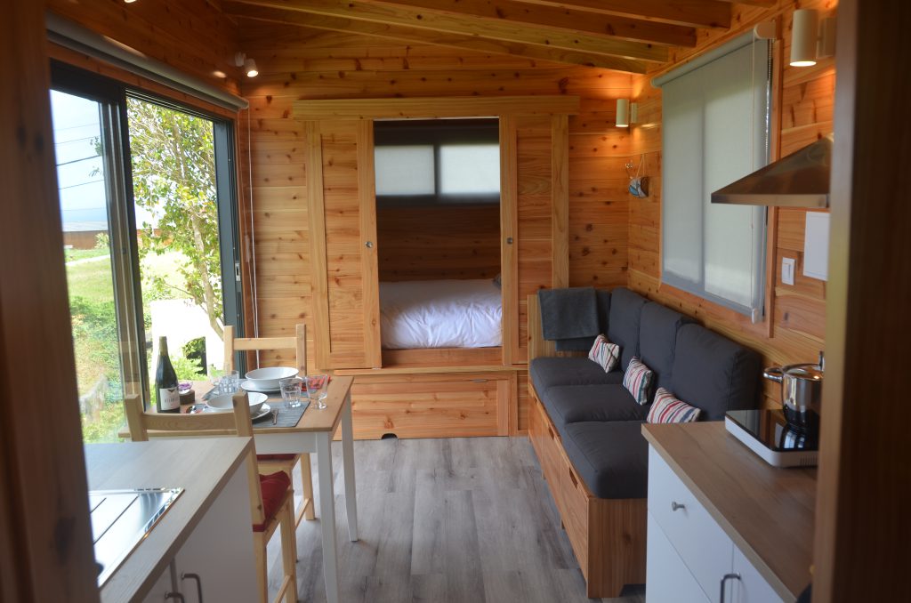 Binnenkant van een Tiny House met keuken, eettafel, bank en bed.