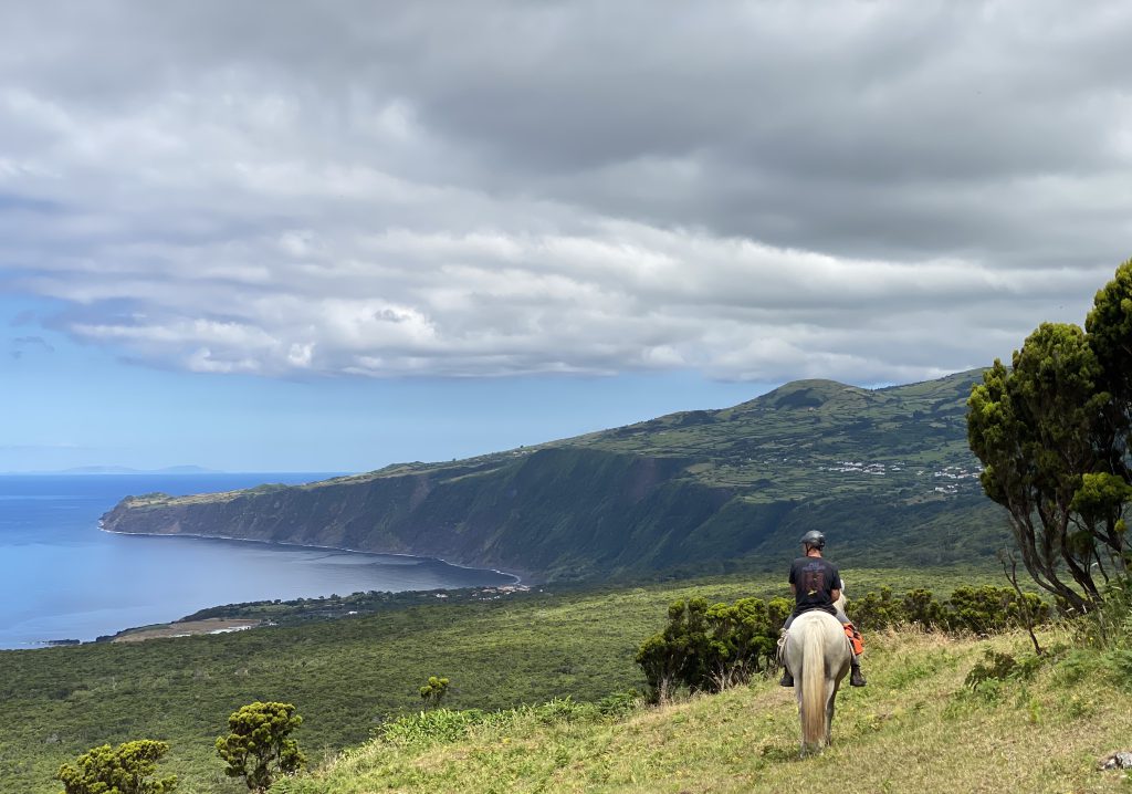 Ruiter en paard kijken uit over de kust van Faial eiland op de Azoren.
