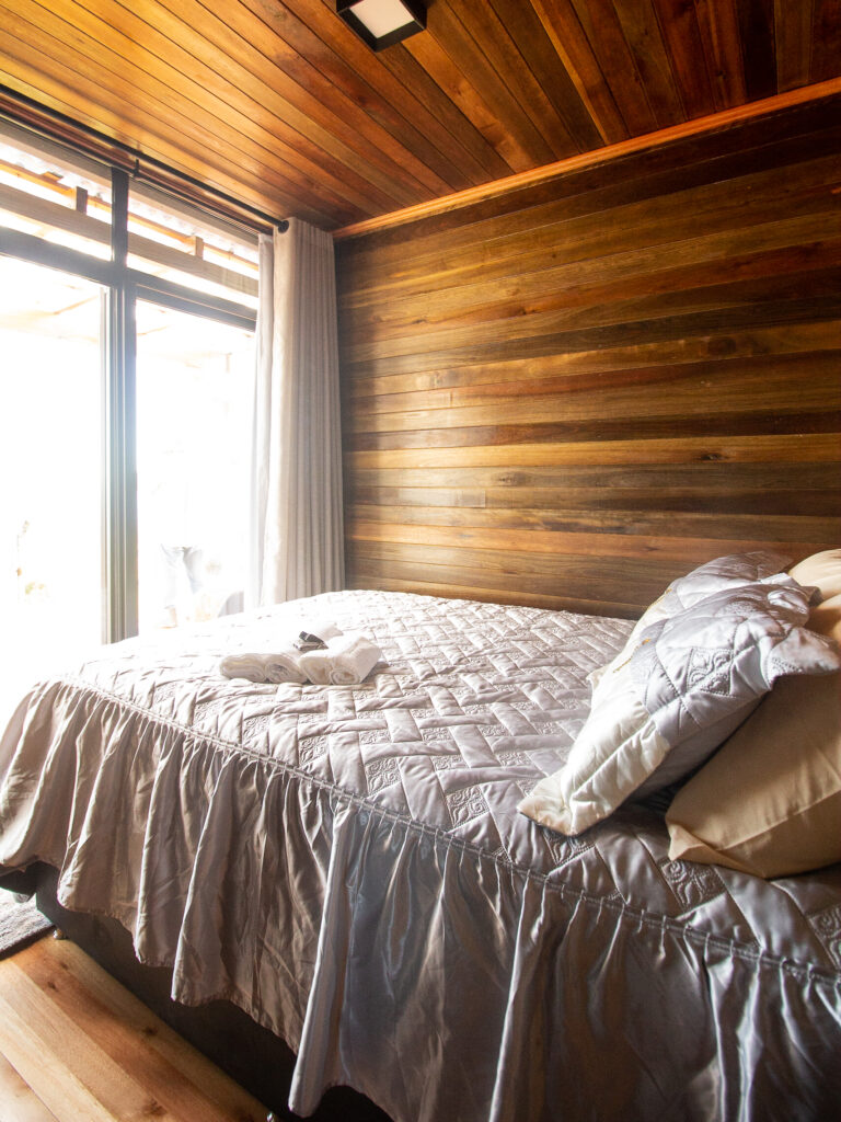 Bed in slaapkamer met houten muren tijdens paardrijvakantie in Brazilië