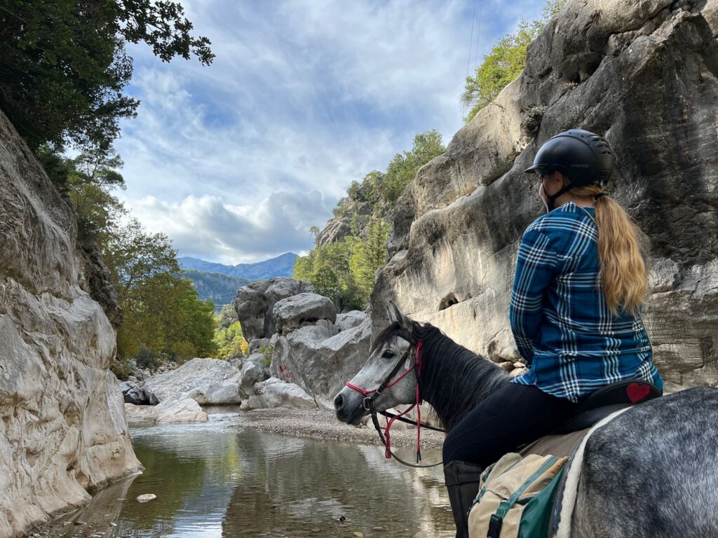 Ruiter en paard kijken uit over een rivier in een ravijn in Turkije.