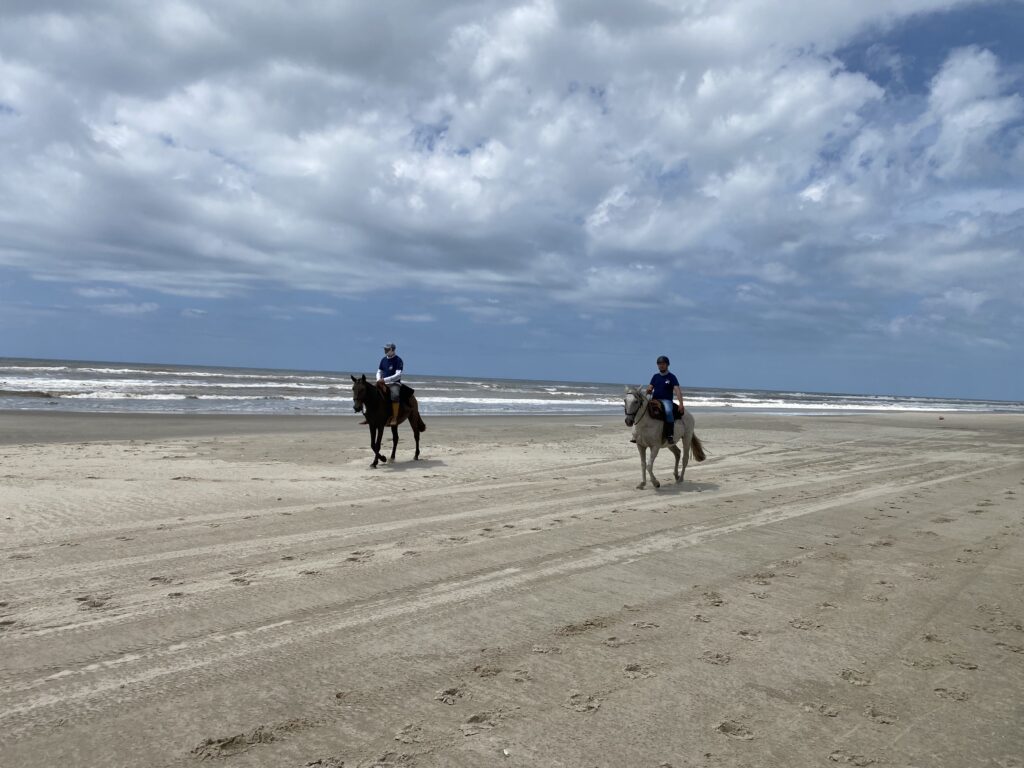 Twee ruiters en paarden tijdens een strandrit in Brazilië