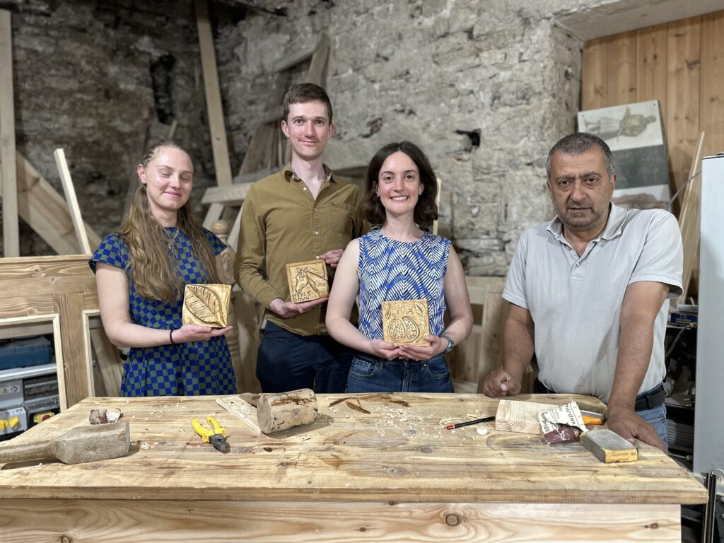 Twee mannen en twee vrouwen laten een houtsnijwerk zien dat ze hebben gemaakt in een workshop in Albanië