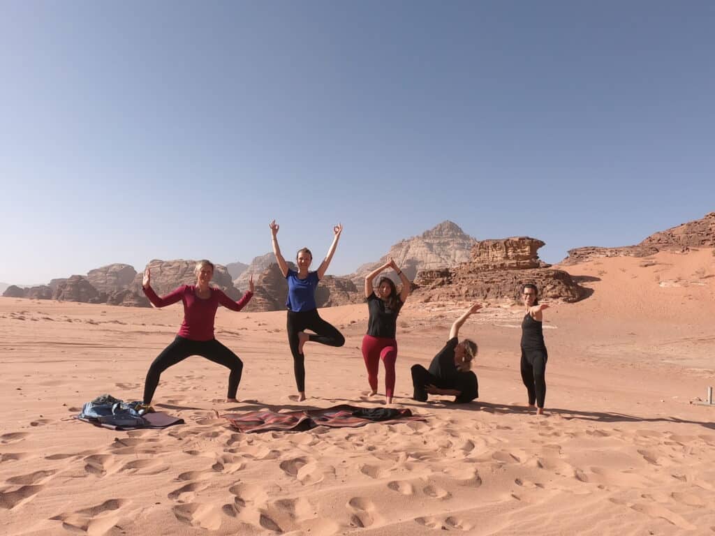 Groep mensen op een zandvlakte met rotsen op de achtergrond in de woestijn van Jordanië