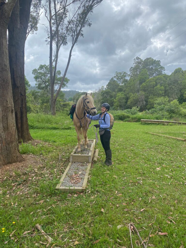 Ruiter naast een paard dat op een obstakel staat in Australië