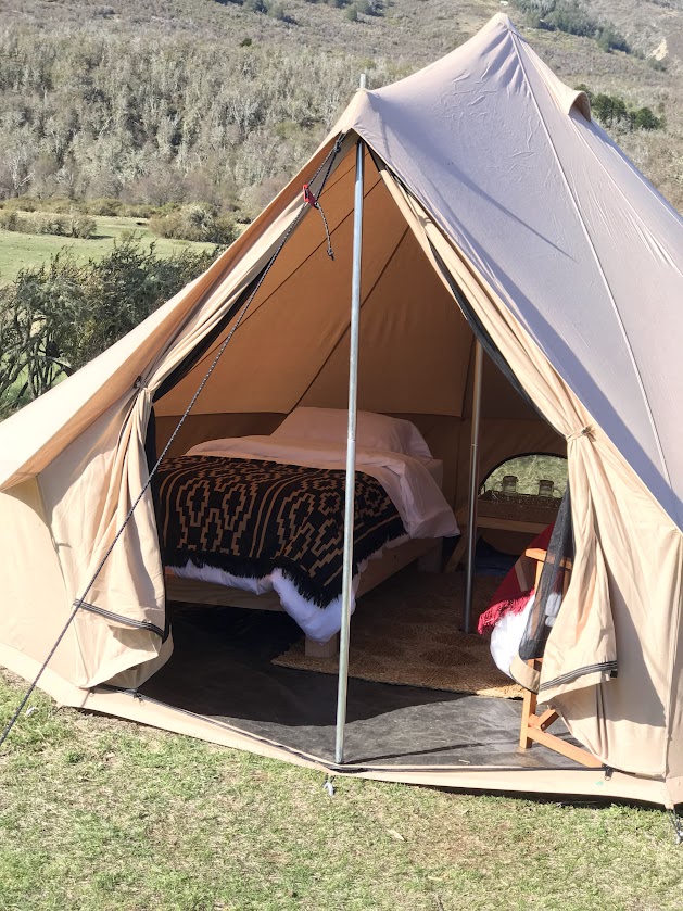 Tent met een opgemaakt bed, nachtkastje en stoel in Patagonië Argentinië