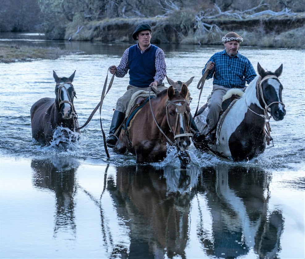 Ruiters en paarden steken een rivier over tijdens een trektocht in Patagonië Argentinië