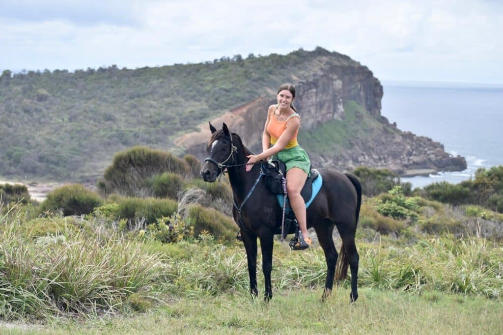 Ruiter en paard op de kliffen bij een strand in Australië