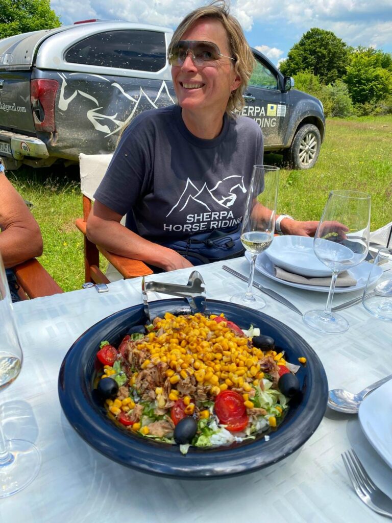 Vrouw met een bord eten op een picknicktafel tijdens de lunch op een trektocht