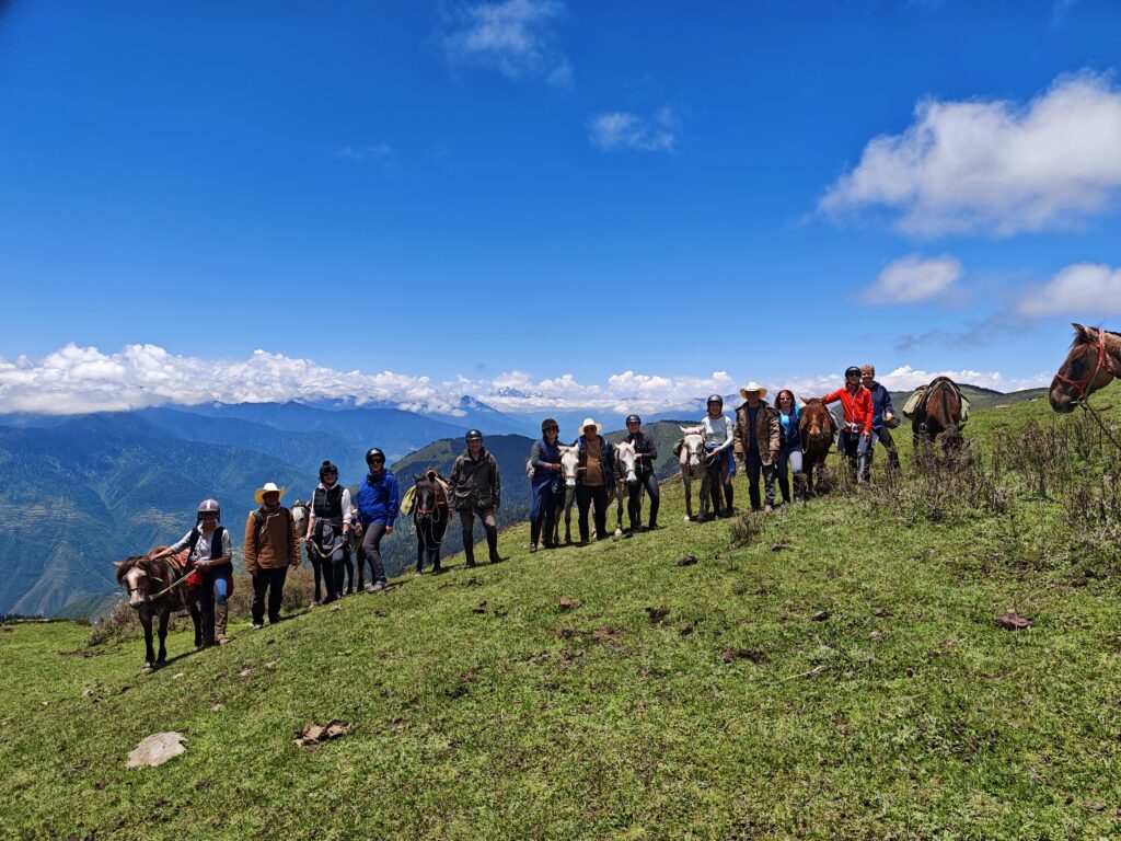 Groep ruiters en paarden op een heuvel met uitzicht op de bergen tijdens een expeditie in China
